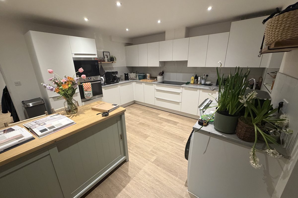 Kitchen in Soham before wrapping, white units and a sage island